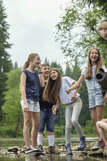 Gruppe fröhlicher Kinder und Jugendlicher bei einem Ausflug in der Natur, organisiert von einer modernen Kinder- & Jugendhilfeeinrichtung, fördert Gemeinschaft und Abenteuerlust.