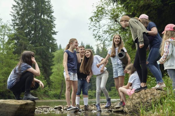 Gruppe fröhlicher Kinder und Jugendlicher bei einem Ausflug in der Natur, organisiert von einer modernen Kinder- & Jugendhilfeeinrichtung, fördert Gemeinschaft und Abenteuerlust.