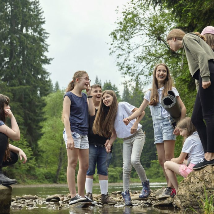 Gruppe fröhlicher Kinder und Jugendlicher bei einem Ausflug in der Natur, organisiert von einer modernen Kinder- & Jugendhilfeeinrichtung, fördert Gemeinschaft und Abenteuerlust.